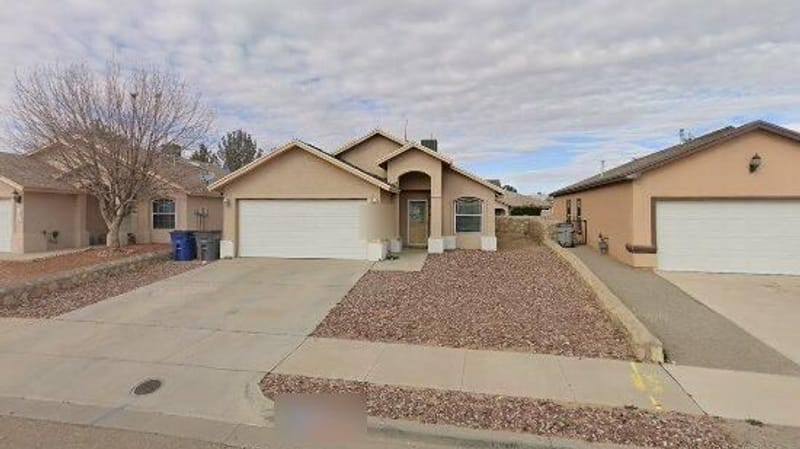 Single-storey tan stucco house with a two-car garage and gravel front yard on the east side of El Paso