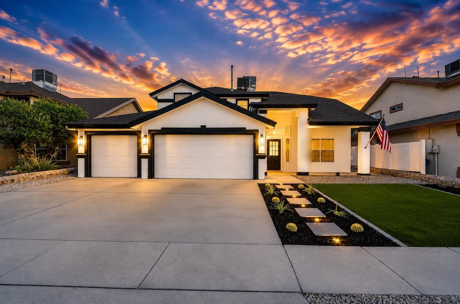 Two-storey stucco house in east El Paso at dusk with a two-car garage and a green front lawn