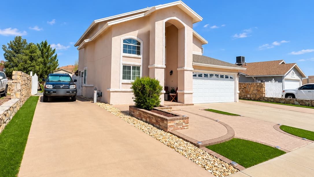 Two-storey pink stucco house in Horizon City with a two-car garage, paver driveway and turf strips
