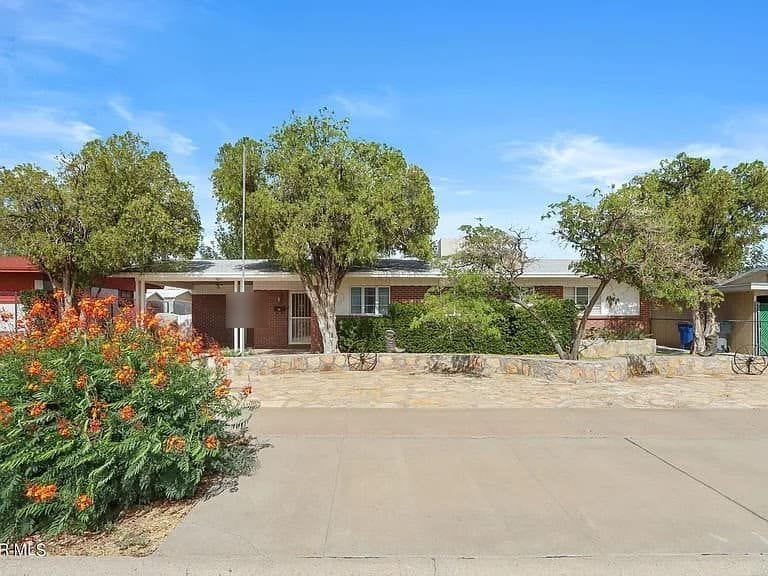 Single-storey 1950s house in northeast El Paso with mature trees and a concrete driveway