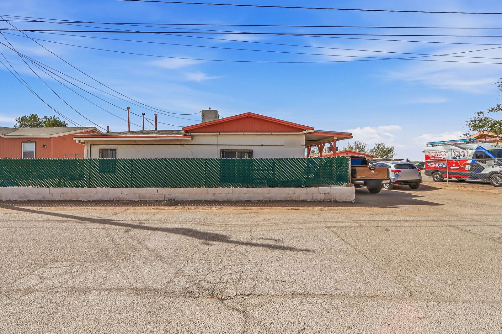 Single-storey duplex in Socorro with a green chain-link fence, seen from the street