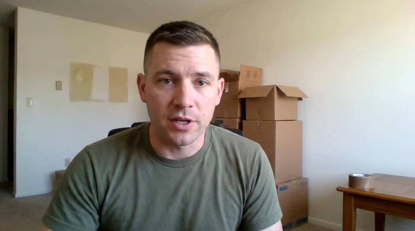 Daniel standing in front of moving boxes before a military relocation.
